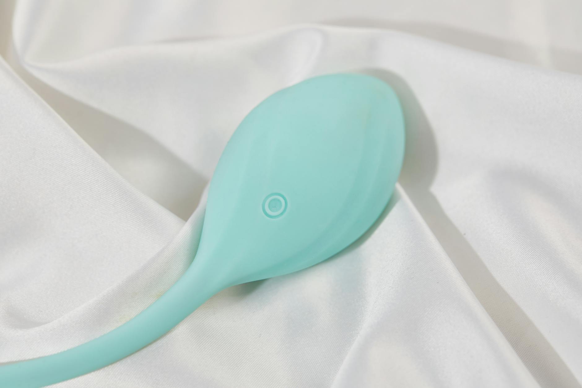 Vibrador de silicona sobre tela de seda blanca suave