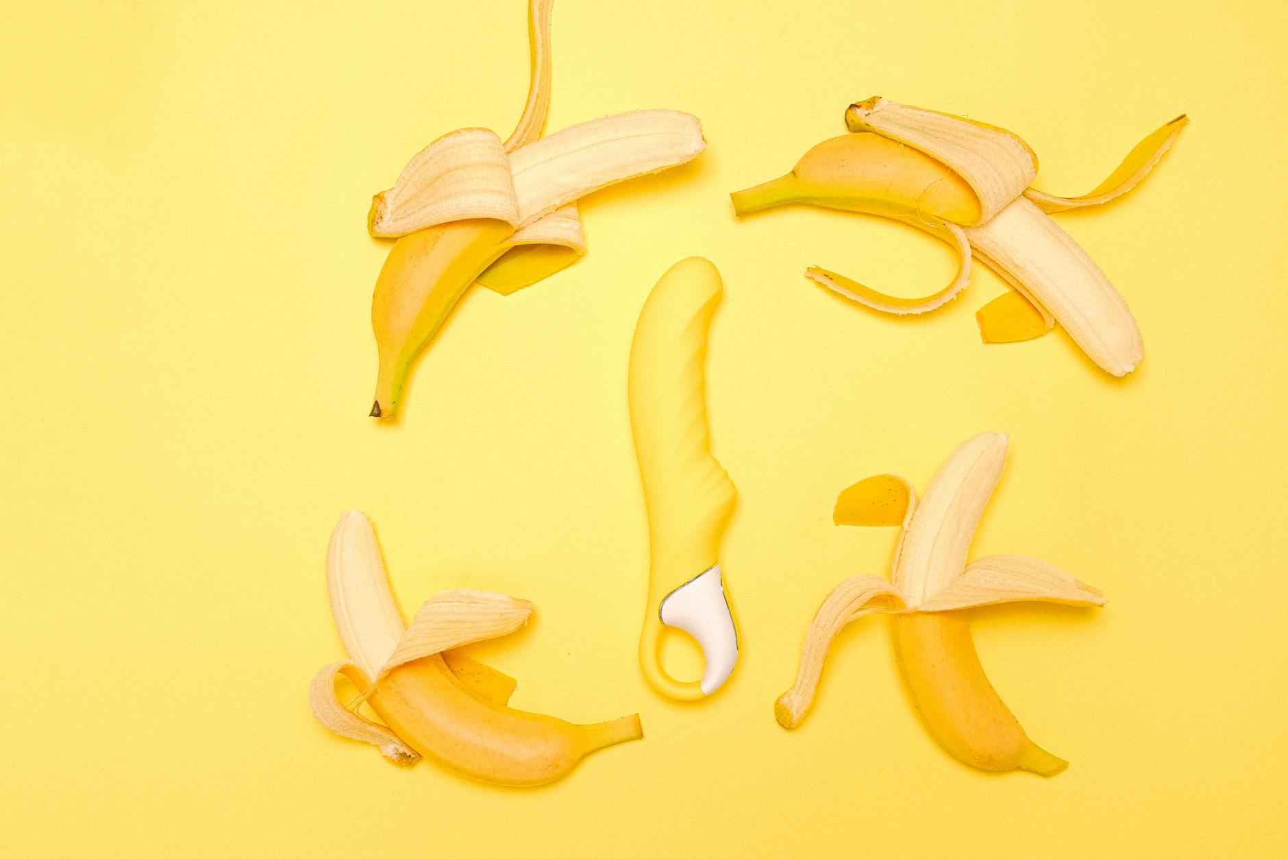 A bright yellow lemon vibrator surrounded by fresh yellow lemons on a vibrant yellow background, symbolizing natural pleasure and sensitivity.