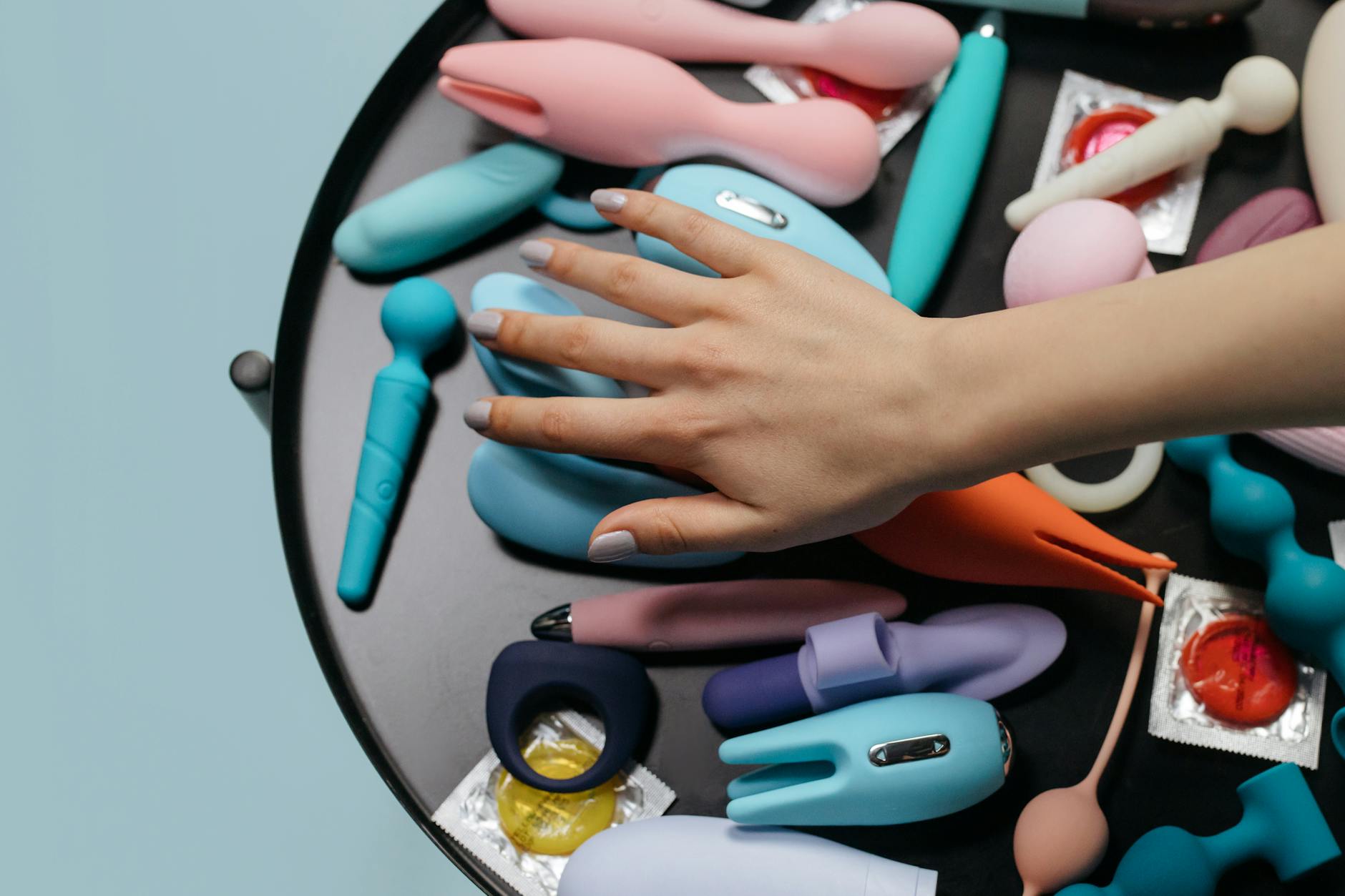 Mujer con gafas sosteniendo vibrador clitorideal de color azul contra fondo morado