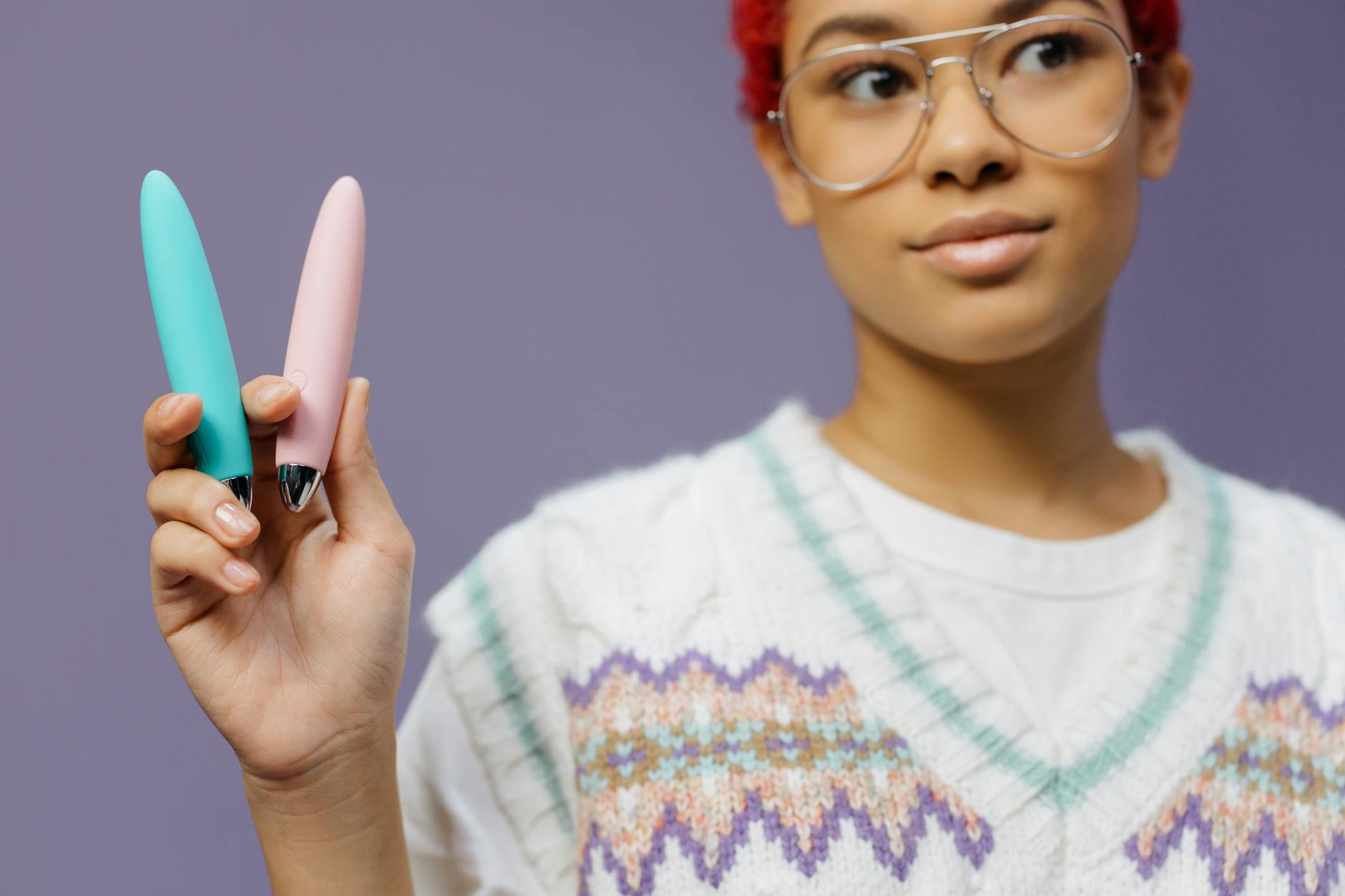 Vibrador de silicona azul sostenido en la mano contra un fondo púrpura sólido, promocionando el auto amor y la sexualidad