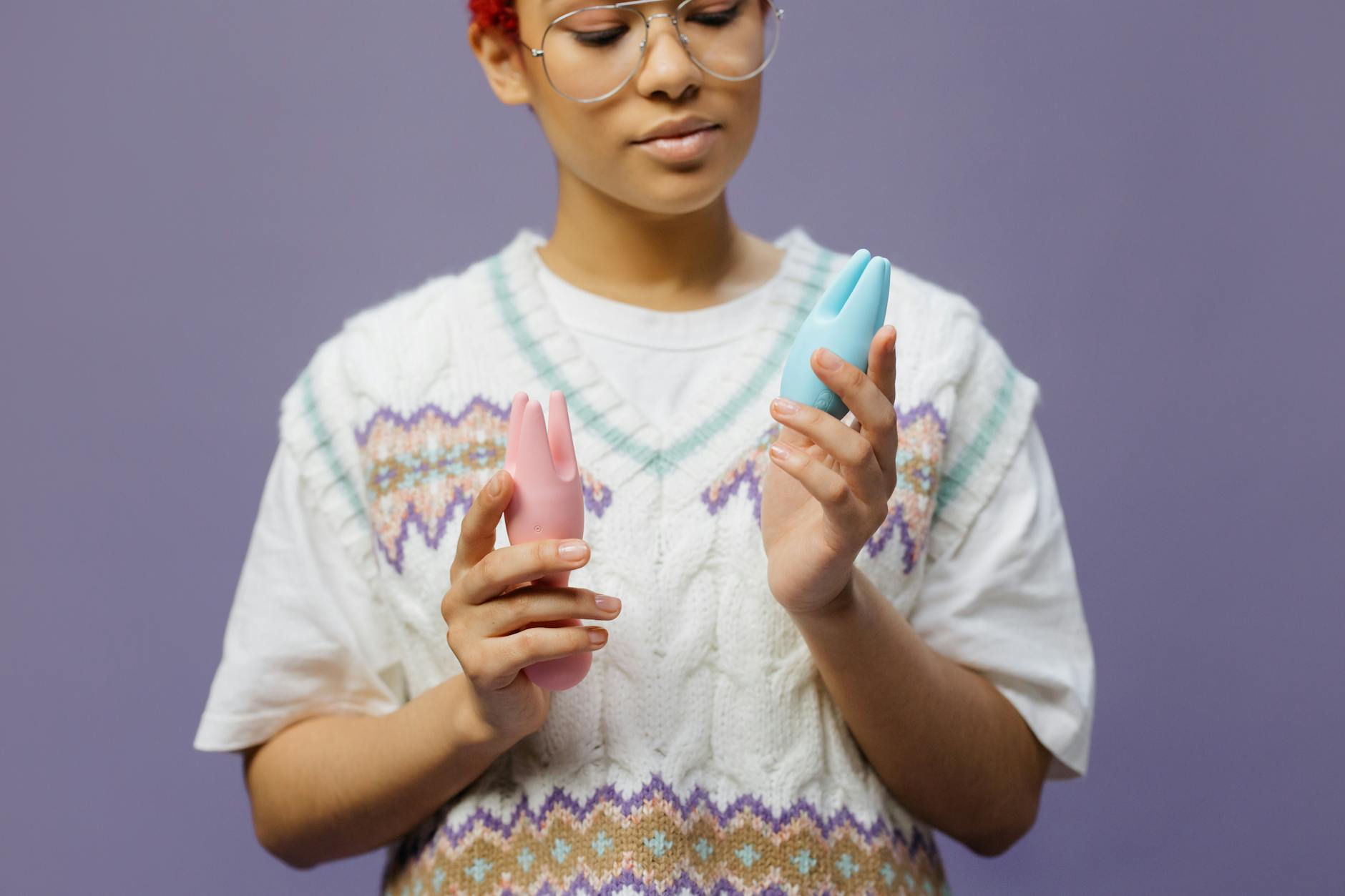 Mujer sosteniendo vibradores de silicona en color azul y rosa con una expresión contemplativa
